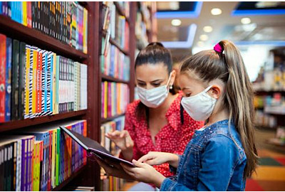 Mutter und Tochter mit Gesichtsmaske Shopping in Buchhandlung, Coronavirus Konzept.